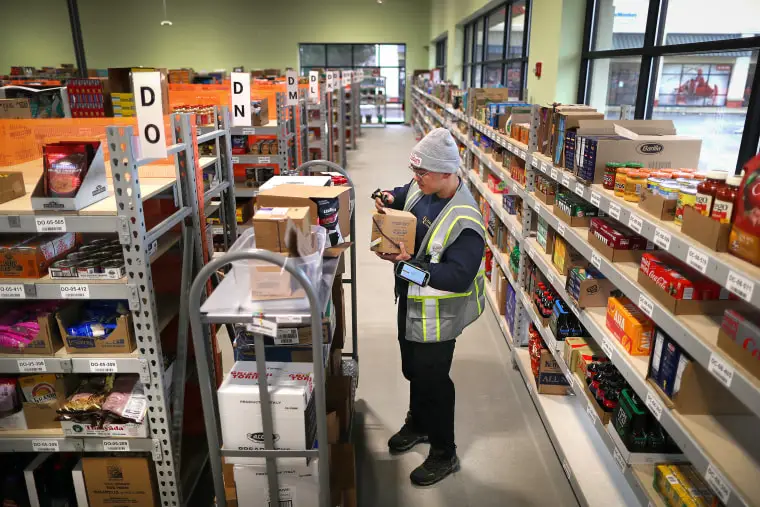 Paul Nguyen stocks shelves inside Addies, a drive-up only grocery store in Norwood, Mass., on Jan. 25.