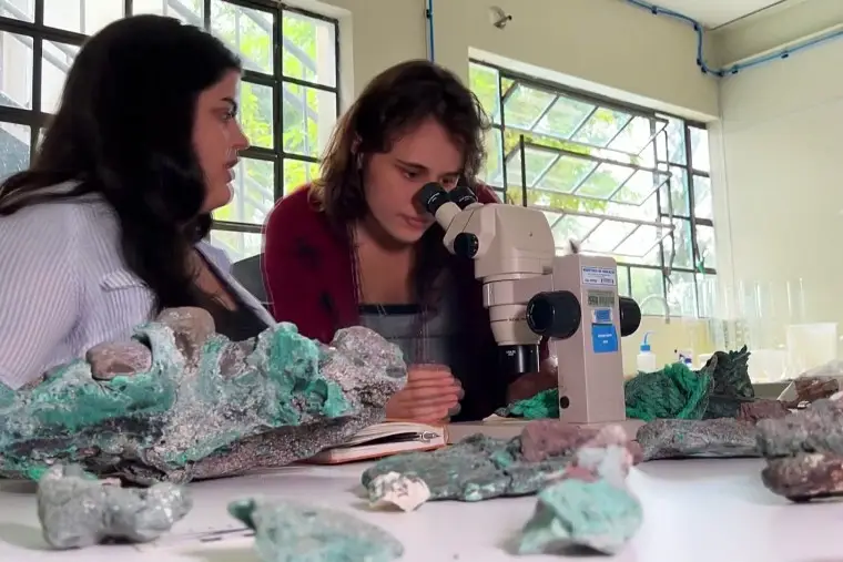 Researcher Fernanda Avelar Santos looks through a microscope next to fellow researcher Giovana Diorio at the Federal University of Parana. 