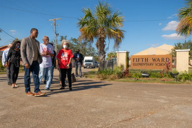 Michael Regan, left, with Robert Taylor, center wearing a white and red T-Shirt, and other community members outside Fifth Ward Elementary School.