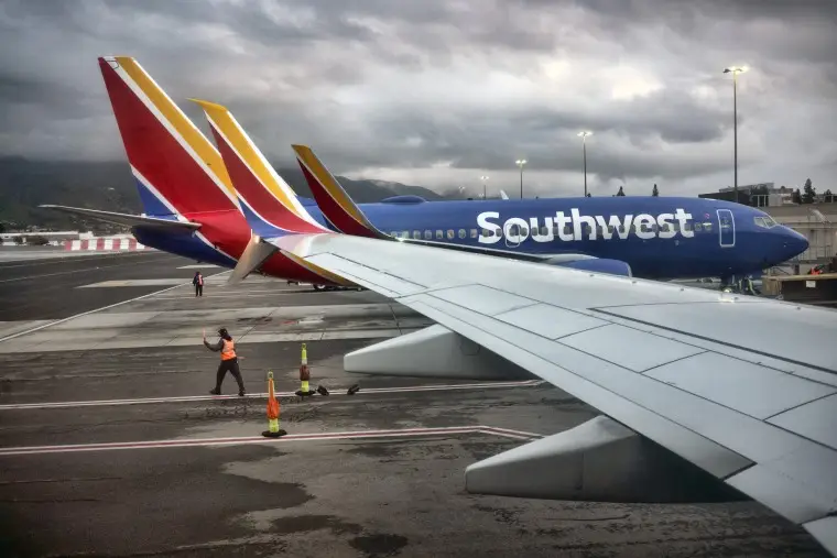 A Southwest Airlines employee directs a plane out of the terminal at Hollywood Burbank Airport in Burbank, Calif.