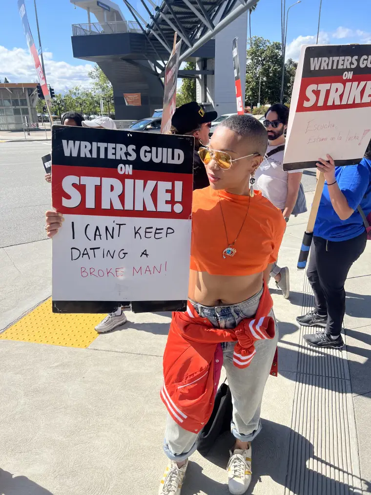 Kyra Jones holds signs while striking with the Writer's Guild