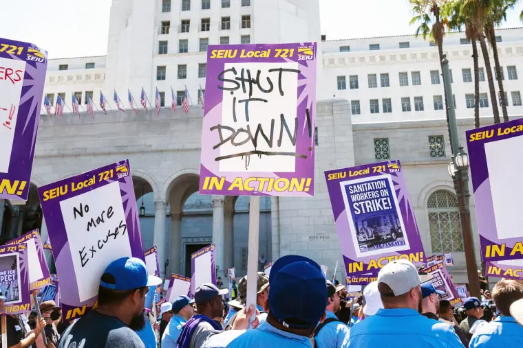 A man holds a picket sign reading “shut it down” as droves of striking workers converged on the steps of Los Angeles City Hall on Tuesday, Aug. 8, 2023.