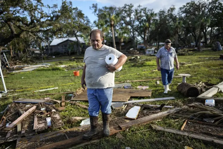 Image: Buddy Ellison, left, and his father Dan look through debris scattered across their property in Horseshoe Beach, Fla., on Aug. 31, 2023, one day after the passage of Hurricane Idalia. 